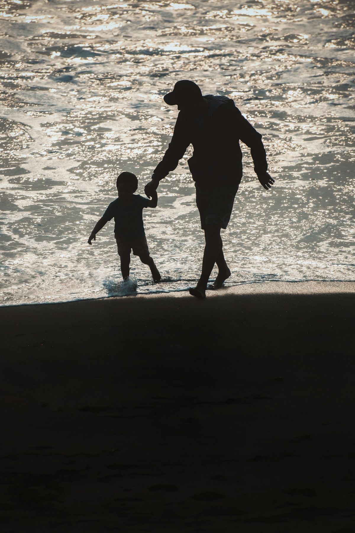 En voksen og et barn som gaar paa stranden
