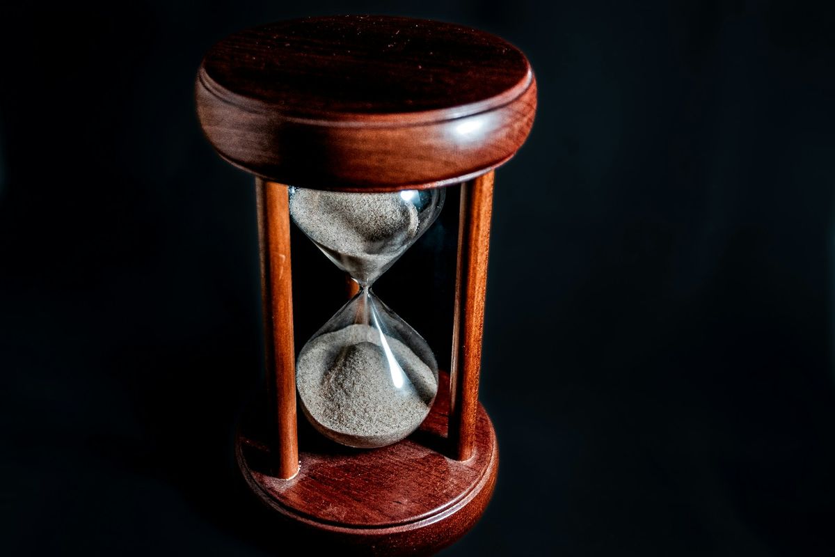 Et timeglass med sand paa moerk bakgrunn som symboliserer frister og tid