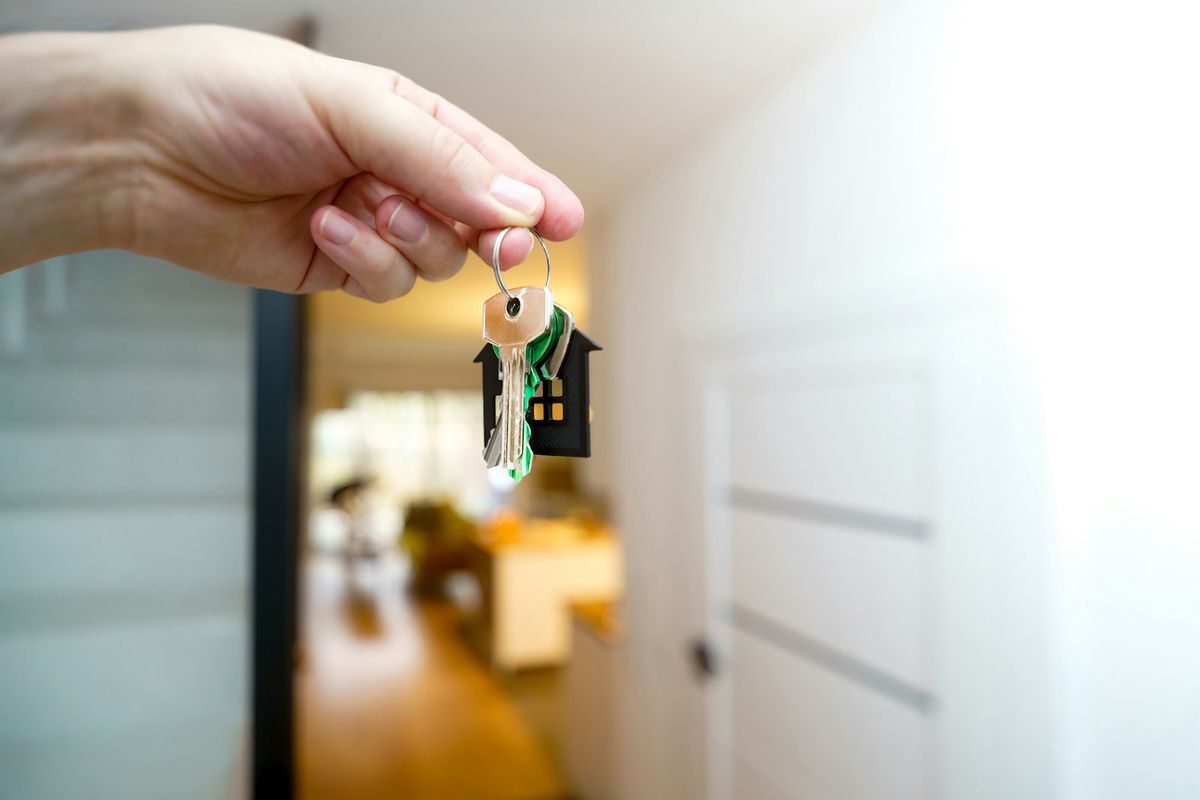 Person holder nøkler foran inngangen til en ny bolig
